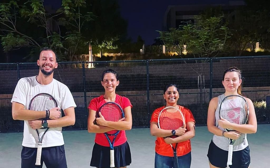 An AK Tennis adult group session on a floodlit court in Dubai
